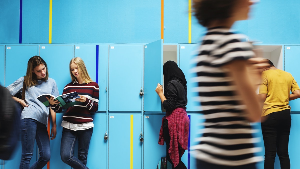 High school students in hallway lined with teal blue lockers