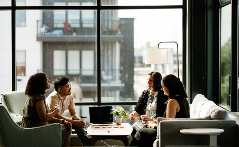 A group of four colleagues sitting around a coffee table and sharing ideas